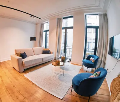 a living room with a white couch and blue chairs at Urbanchic Appartement élégance hyper centre in Liège