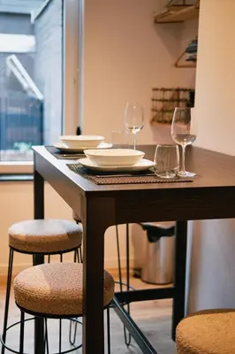 a wooden table with wine glasses and plates on it at Urbanchic Appartement cosy 1B in Liège