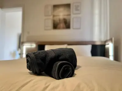 a black towel laying on top of a bed at Modern Business Flat - Courts et moyens séjours in Liège