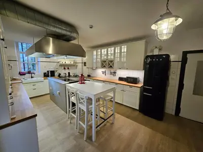 a kitchen with a black refrigerator and a white table at Das GANZE Chateau Thor - bis zu 22 Personen in Lontzen