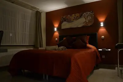 a bedroom with a bed with an orange bedspread at B&B Noord-Zuid in Zonhoven