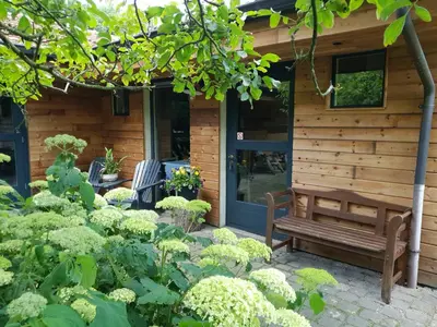 a garden with a bench in front of a building at B&B Land of Tir Nan Og in Lommel