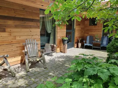 a wooden house with a rocking chair in a yard at B&B Land of Tir Nan Og in Lommel