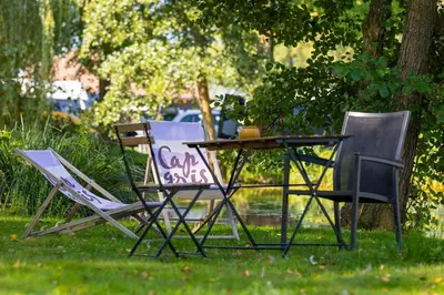two chairs and a table with a sign on it at Vakantiehuis 25 min Roermond Maasmechelen Maastricht in Kinrooi