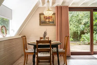 a dining room with a table and chairs and a window at Boshuisje Rekem - Fleur in Lanaken