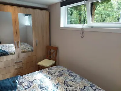 a bedroom with a bed and a cabinet and two windows at Opeteukske in Lanaken