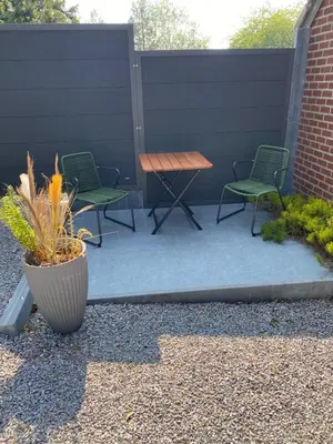a patio with two chairs and a wooden table at Au nid douillet in Trooz