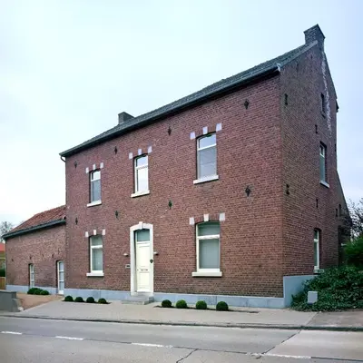 a red brick building with a white door at A la Maison in Heks