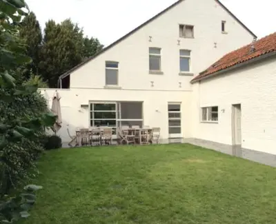a white building with a table and chairs in a yard at A la Maison in Heks