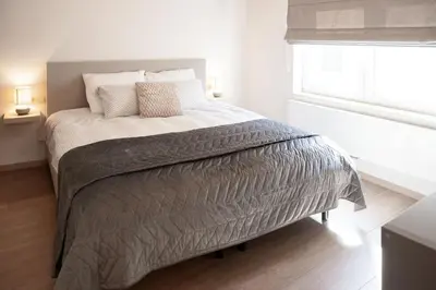 a bed in a white bedroom with a window at Vakantiewoning Huis 8 in Tongeren