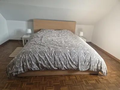 a bed with a silver comforter in a bedroom at Appartement à la campagne in Juprelle