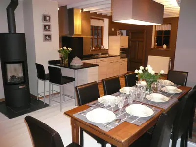 a dining room with a table and a kitchen at Gite des Comagnes in Limbourg