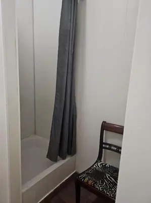 a bathroom with a shower curtain and a chair at Logements Liège un in Liège