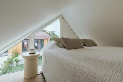 a white bed in a room with a large window at Chalet Eau Vive Mase in Maaseik