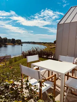 a white table and chairs with a view of a lake at Chalet Eau Vive Mase in Maaseik