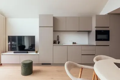 a kitchen with white cabinets and a table and chairs at Chalet Eau Vive Mase in Maaseik