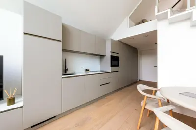 a kitchen with white cabinets and a table and chairs at Chalet Eau Vive Mase in Maaseik