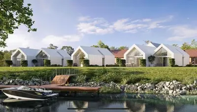 a boat on the water in front of some houses at Chalet Eau Vive Mase in Maaseik