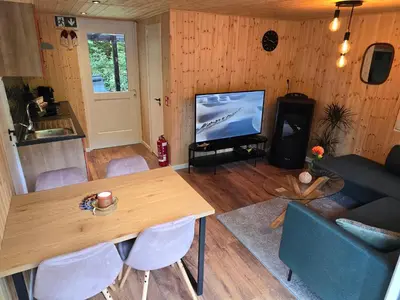 a living room with a table and a television at Tiny Lodge met prive Jacuzzi in Lanaken