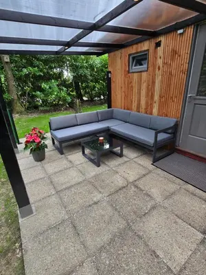 a patio with a blue couch and a table at Tiny Lodge met prive Jacuzzi in Lanaken