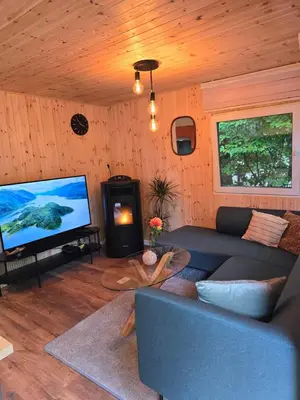 a living room with a couch and a flat screen tv at Tiny Lodge met prive Jacuzzi in Lanaken