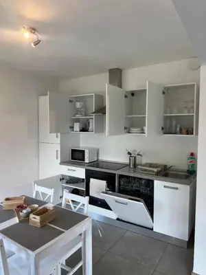 a kitchen with white cabinets and a table at Comme chez vous in Soumagne