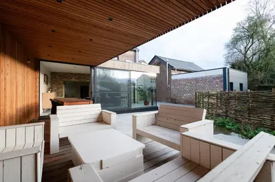 a patio with white benches on a wooden deck at Vakantiehuis Remersdaal in Voeren