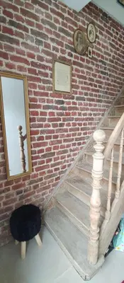 a staircase with a mirror and a brick wall at Au petit 31 in Pepinster