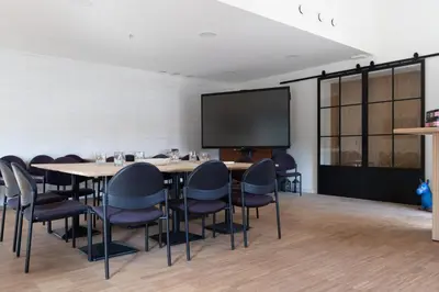 a conference room with tables and chairs and a large screen at Lindehoeve in Heusden - Zolder