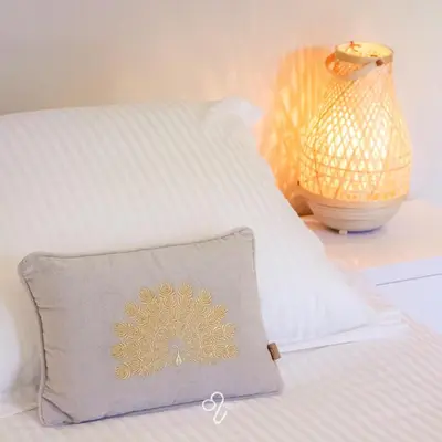 a pillow sitting on a bed next to a lamp at La Maison de Rose in Riemst