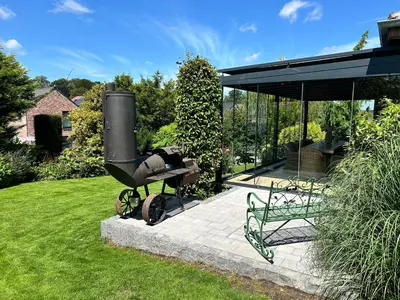 a barbecue grill and a bench in a yard at La Maison de Rose in Riemst