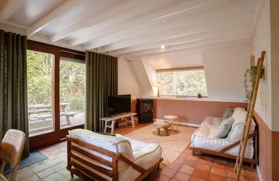 a living room with a couch and a tv at Boshuisje Rekem - Olive in Lanaken