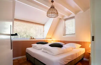 a bedroom with a bed with white pillows at Boshuisje Rekem - Olive in Lanaken