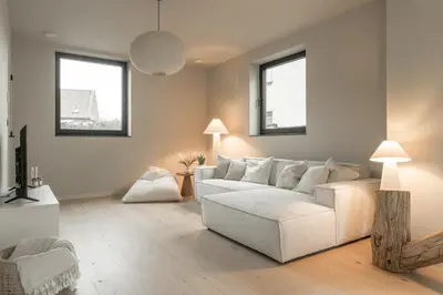 a living room with a white couch and two windows at Vakantie aan de Maas - Vakantiewoning Leenhof in Kinrooi