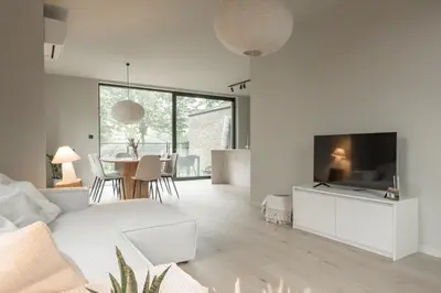 a living room with a white couch and a tv at Vakantie aan de Maas - Vakantiewoning Leenhof in Kinrooi