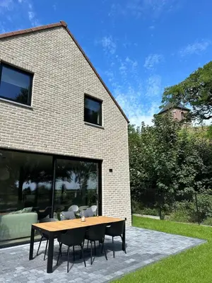 a table and chairs in front of a building at Vakantie aan de Maas - Vakantiewoning Neerhof in Kinrooi