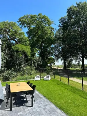 a wooden table and chairs in a park at Vakantie aan de Maas - Vakantiewoning Neerhof in Kinrooi