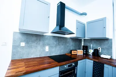 a kitchen with white cabinets and a wooden counter top at Chambre R2 avec salle de bain partagée près de l'hôpital de la Citadelle à Liège in Liège