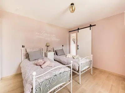 two beds in a bedroom with white walls and wood floors at Vakantiehuis Bonne Home in Bree