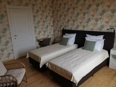 a bedroom with two beds and a chair and a door at Manoir du Moulin in Berloz