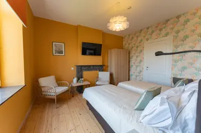 a hotel room with two beds and a table and chairs at Manoir du Moulin in Berloz