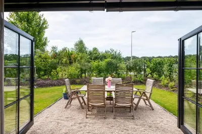 a patio with a table and chairs looking out onto a garden at Stee10 in Lanaken