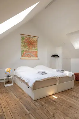 a white bedroom with a bed and a painting on the wall at Chill Hill in Hasselt