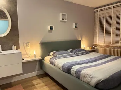a bedroom with a bed with a green headboard and a window at Romagna in Tongeren