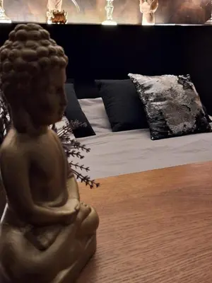 a statue sitting on a table next to a bed at Maison Beau in Zonhoven