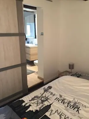a bedroom with a bed and a bathroom with a sink at La Vie Hors Château in Liège