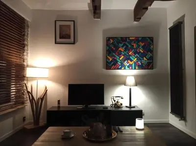 a living room with a television and two lamps at La Vie Hors Château in Liège