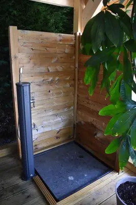 an outdoor shower with a wooden wall at Luxury House in Remersdaal