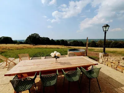 a wooden table with chairs and a vase of flowers at La Petite Maison dans la Prairie in Pepinster