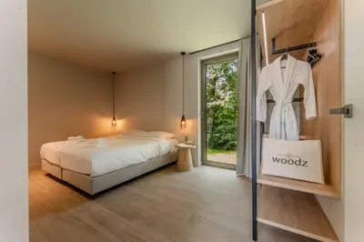 a bedroom with a bed and a dress hanging on a rack at Suite - 2 personen - Woodz Lodges in Heusden - Zolder